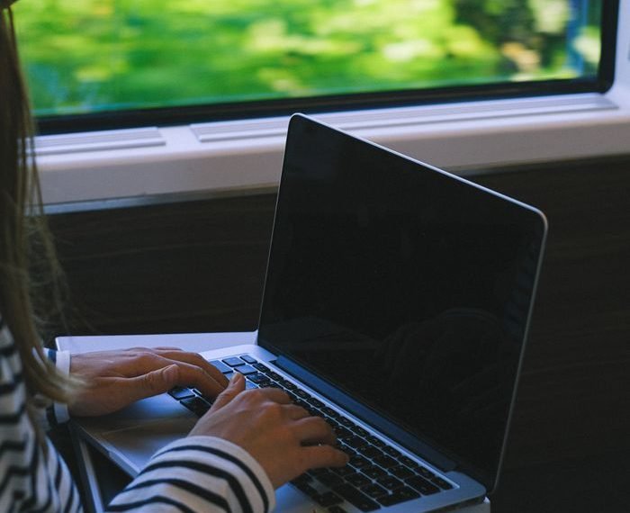 A woman typing on a laptop while traveling on a train, capturing the essence of mobile work lifestyle.