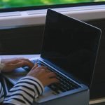 A woman typing on a laptop while traveling on a train, capturing the essence of mobile work lifestyle.