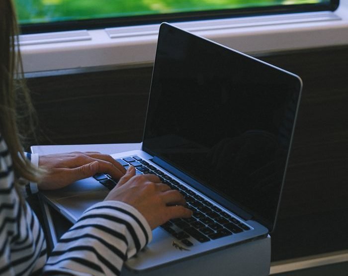 A woman typing on a laptop while traveling on a train, capturing the essence of mobile work lifestyle.