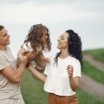 A joyful family moment outdoors with parents playing with their daughter.
