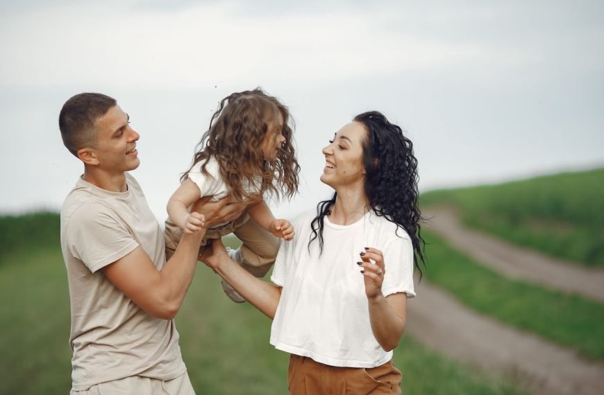 A joyful family moment outdoors with parents playing with their daughter.