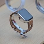 Close-up of a sleek smartwatch with a leather strap displayed on a wooden surface.