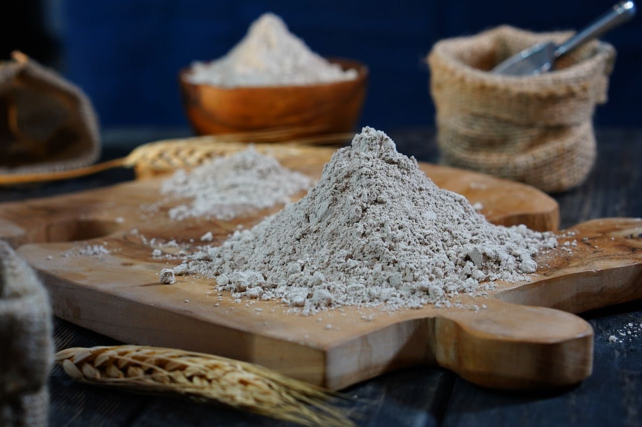 Close-up of flour on a wooden board with scattered grains for baking moods.