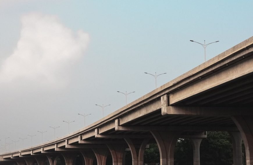 A concrete viaduct stretches beneath a clear blue sky. Captured in Dhaka, Bangladesh.
