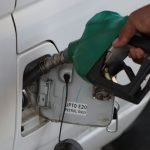 Close-up of a hand refueling a vehicle. E20 petrol pump nozzle in use.