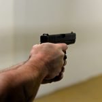 High angle of crop faceless male firing gun to target in shooting range