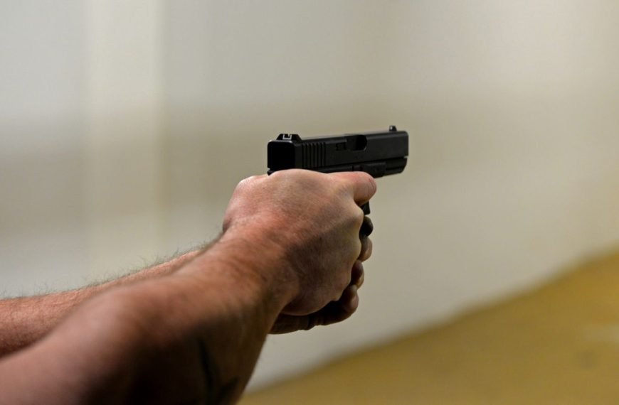 High angle of crop faceless male firing gun to target in shooting range