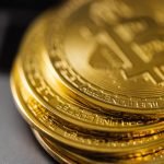 Close-up of a stack of shiny gold bitcoins on a computer keyboard, symbolizing digital currency.