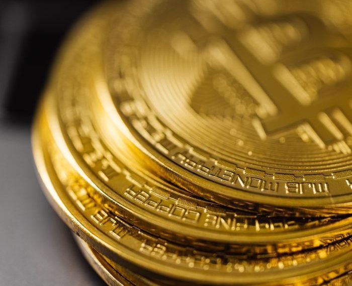 Close-up of a stack of shiny gold bitcoins on a computer keyboard, symbolizing digital currency.