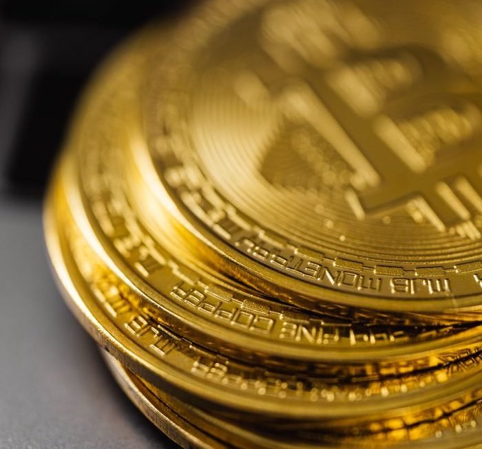 Close-up of a stack of shiny gold bitcoins on a computer keyboard, symbolizing digital currency.