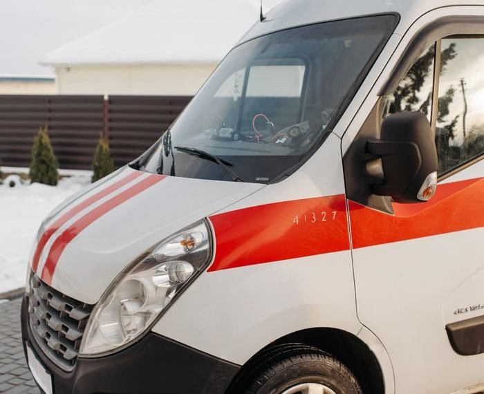 Close-up of a red and white ambulance vehicle parked outdoors during the day.