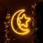 Neon crescent moon with star and floral garland, ideal for festive decor.